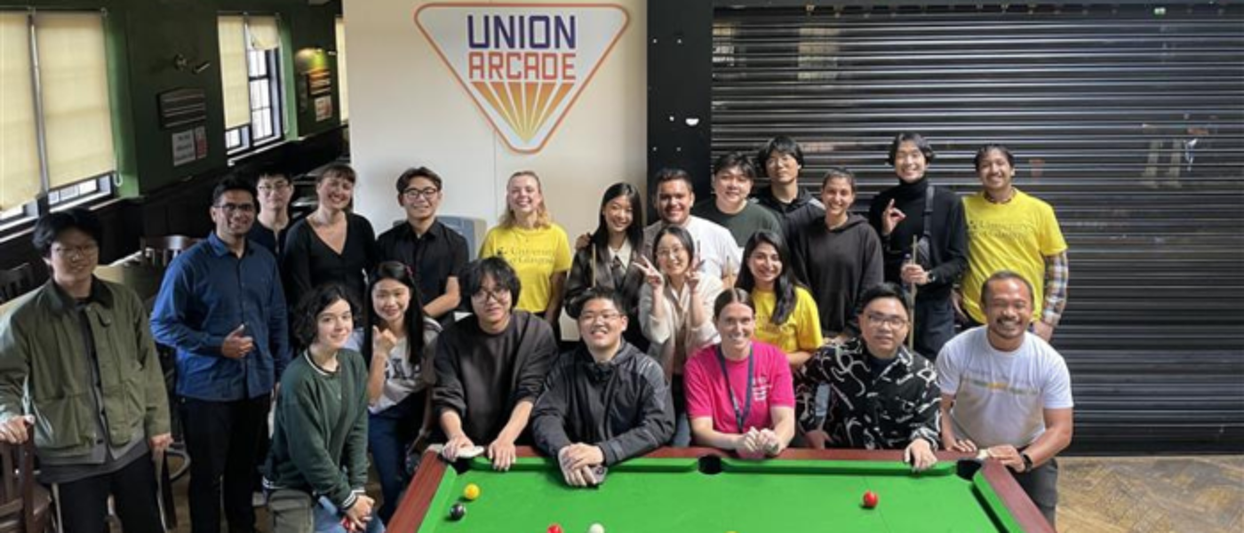 a large group of students stand smiling behind a pool table