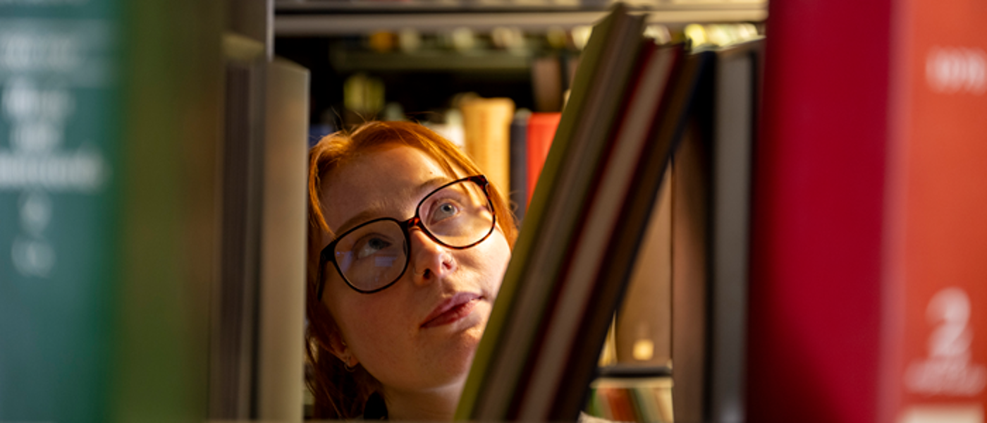 A student looks at books on a library shelf