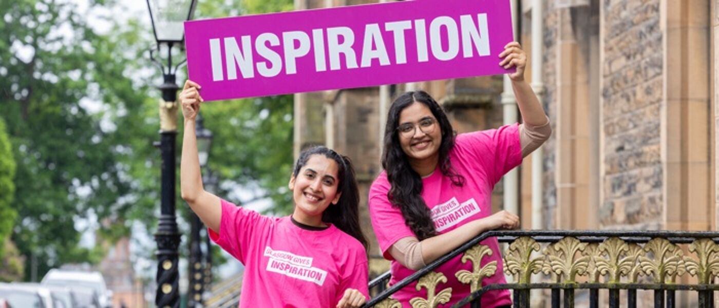 two students in pink t-shirts holding a banner with inspiration on it