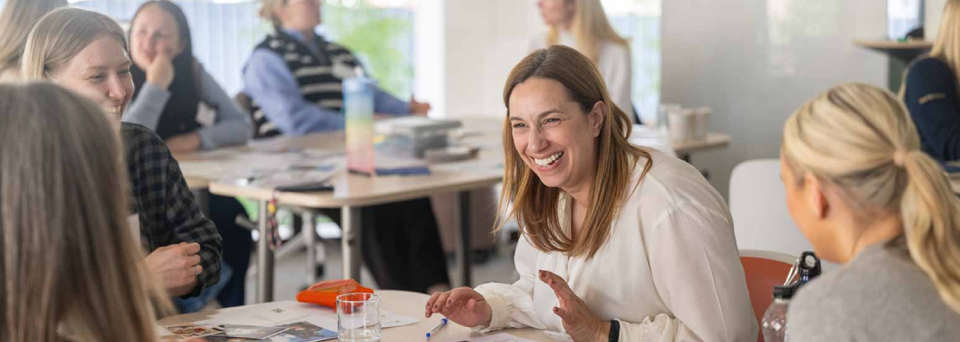 Professionals smiling and laughing seated around a table in an office environment