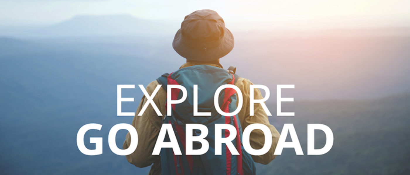 Person wearing hat and backpack and looking at distant view with text: Explore Go Abroad