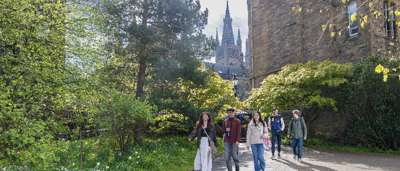 Five students walk through Professors' Walk with the University Tower in the background