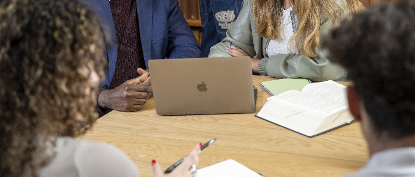 A group of people gather around a laptop at a desk