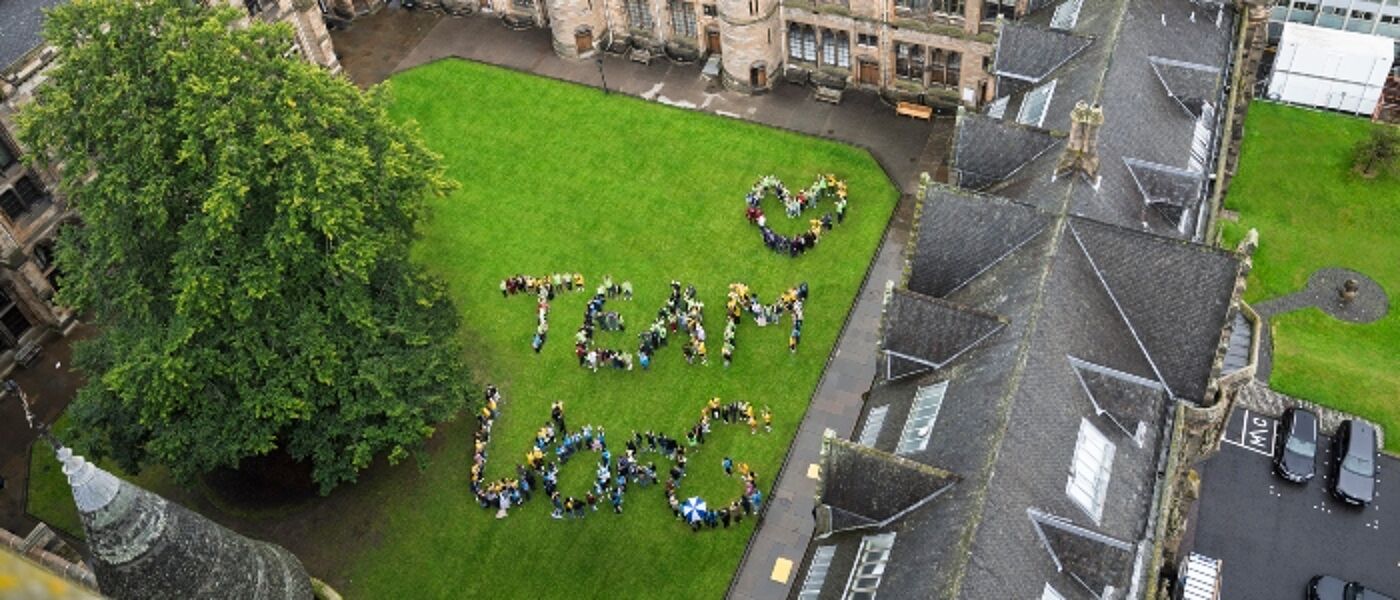 Students in the East Quadrangle, University of Glasgow, standing to form the phrase 'Team UofG'