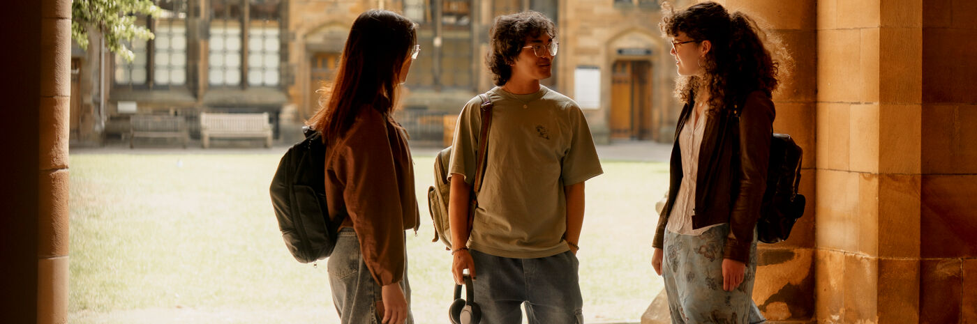 Three students stood talking in the cloisters