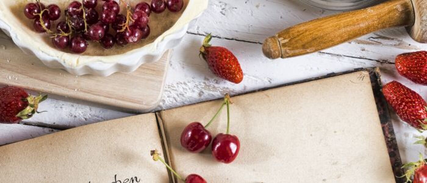 Open book with cherries on top of page and other berries around it.