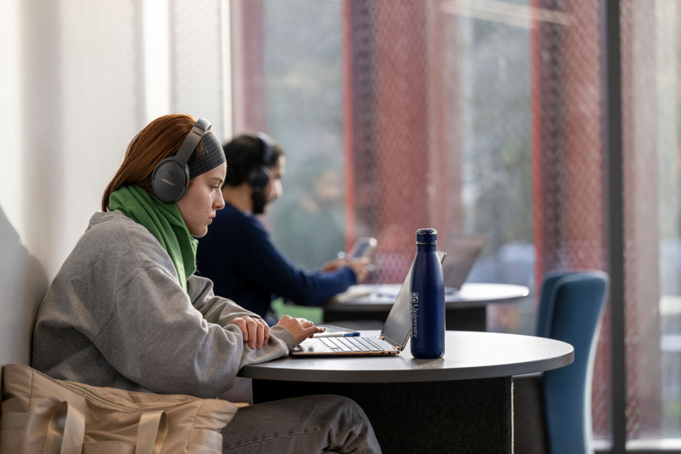 Student with headphones on, on their laptop, studying on their own.