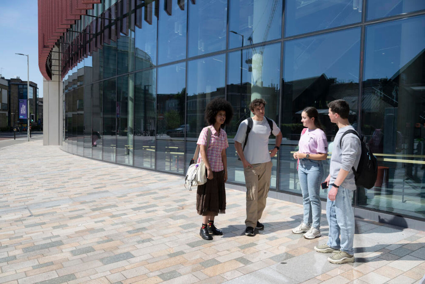 A group of 4 students standing talking outside the JMS building.
