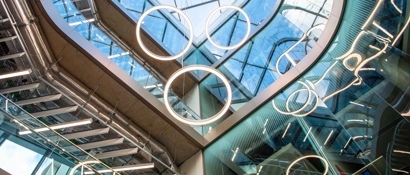 Circular lights hanging from the roof of a glass-ceilinged atrium