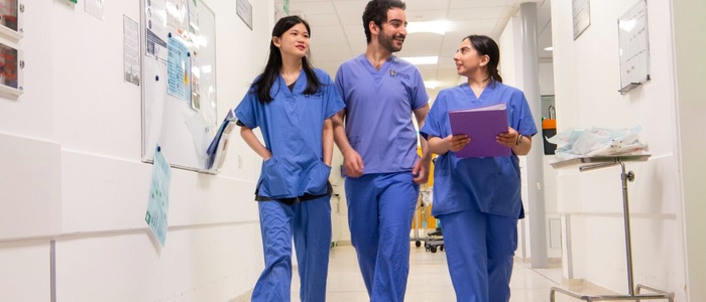 3 medical people walking wearing blue scrubs