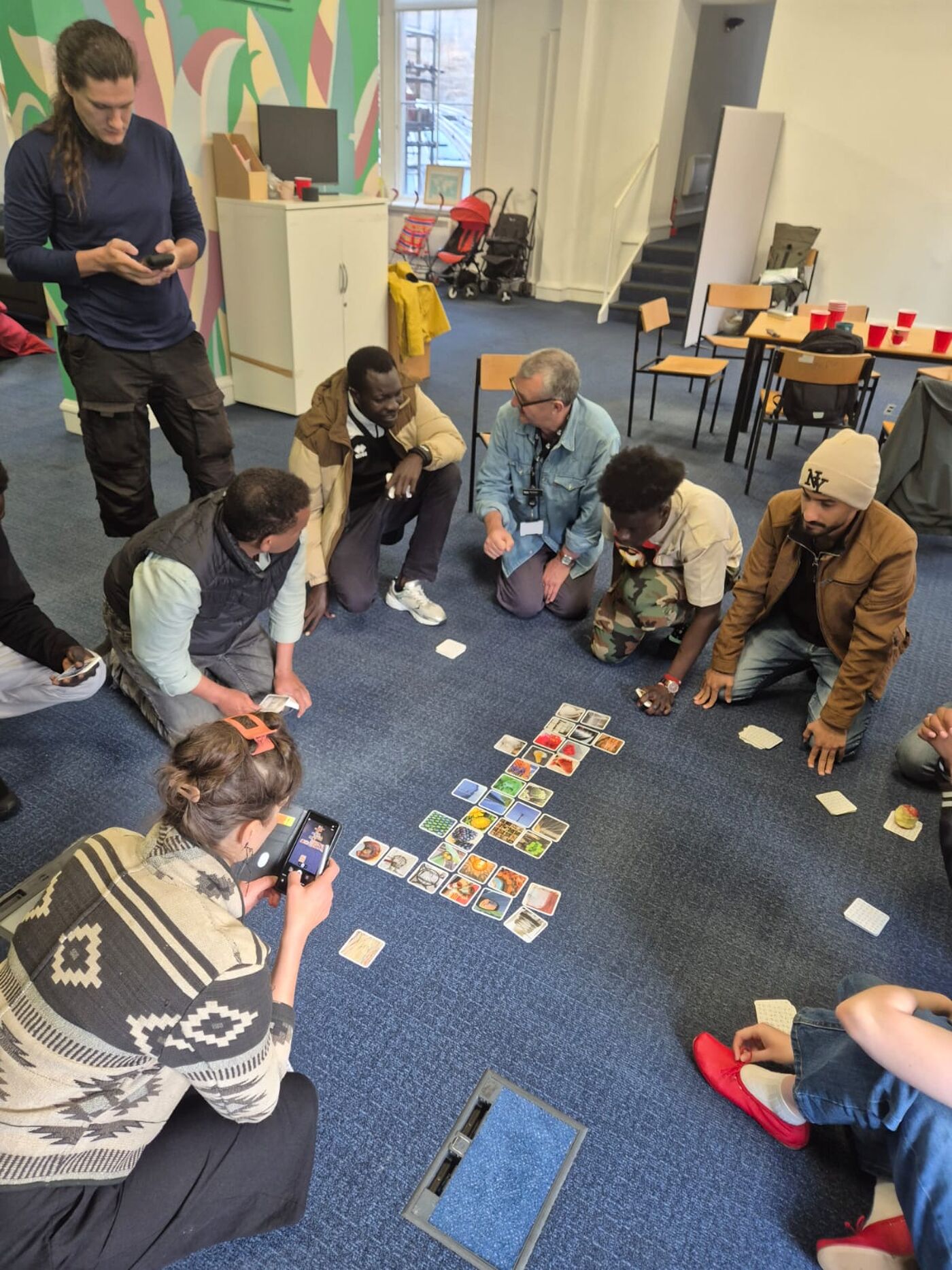A group sits together during a workshop, discussing and arranging picture cards as part of a collaborative activity.