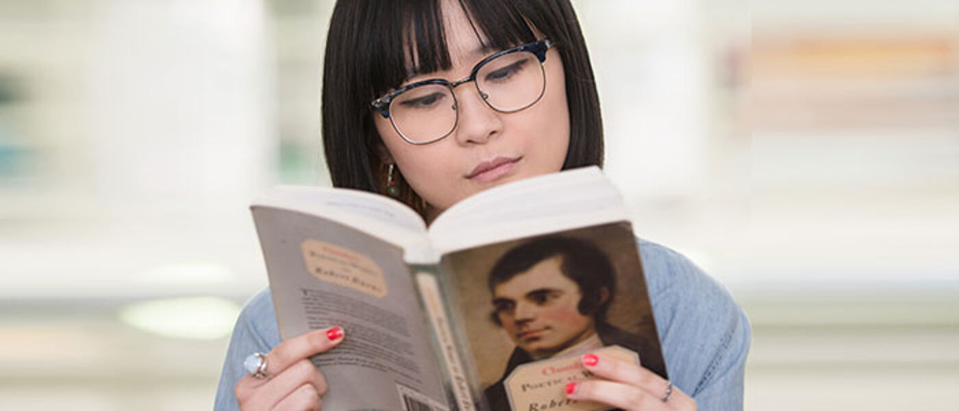 Female student reading a book of Robert Burns work