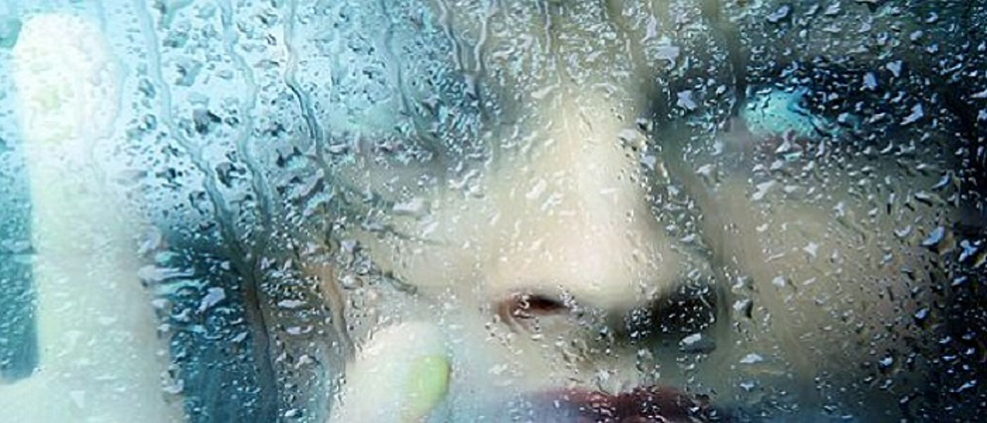 woman at rainy window tile About us