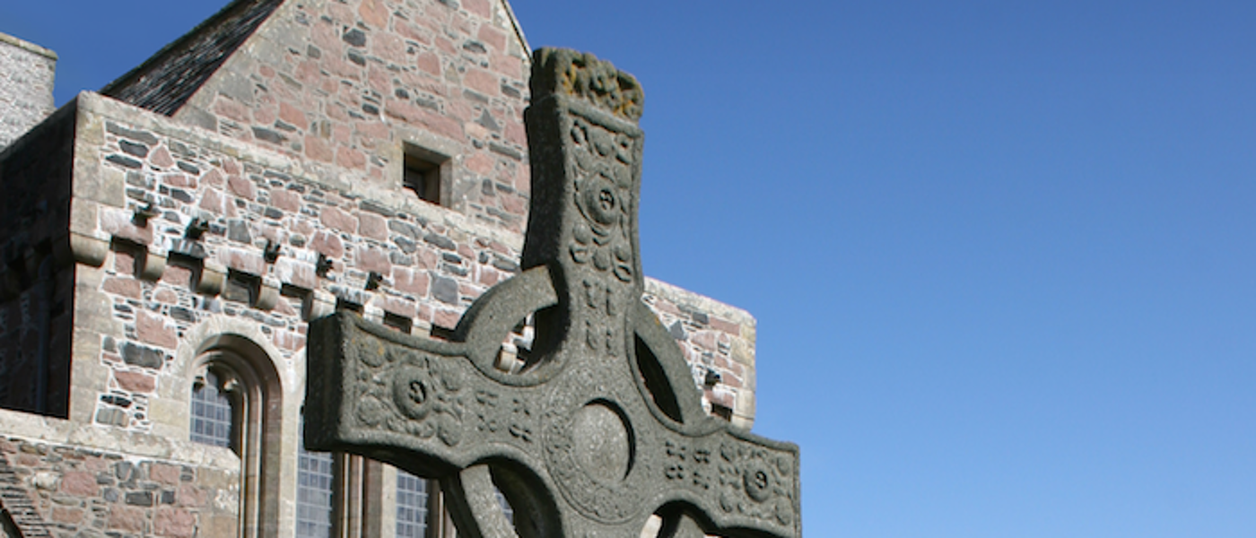Photograph of a stone church with a stone crucifix standing outside