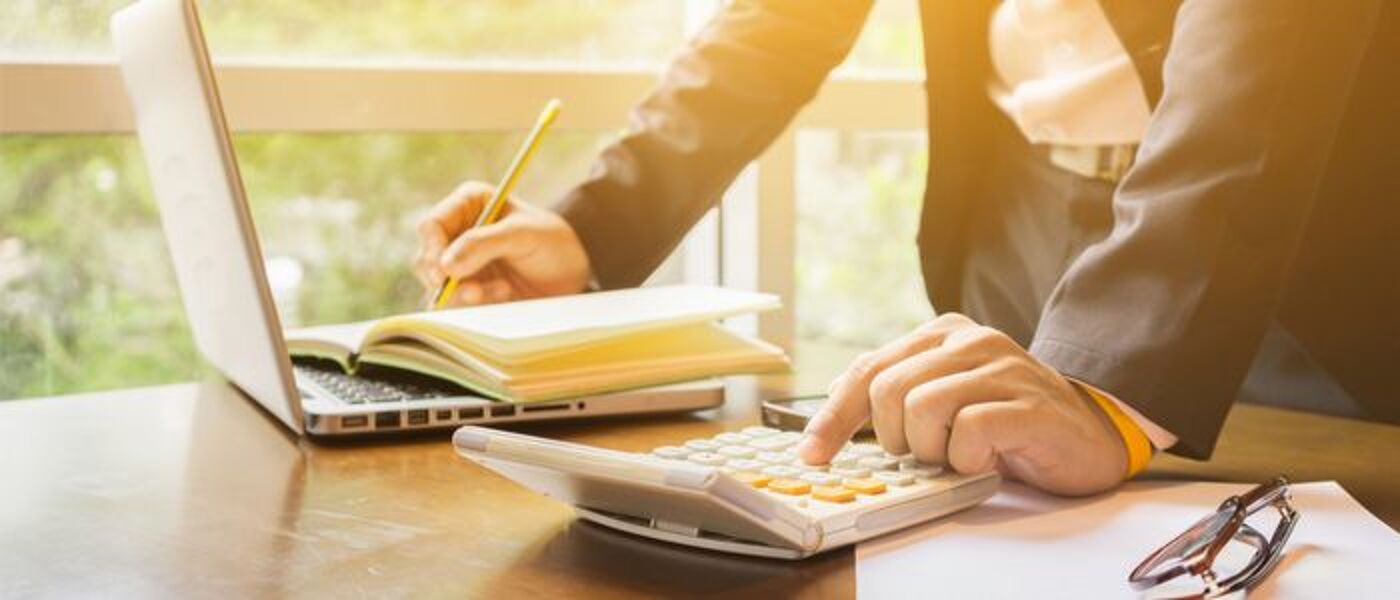 Image of an individual using a calculator and writing in a notebook
