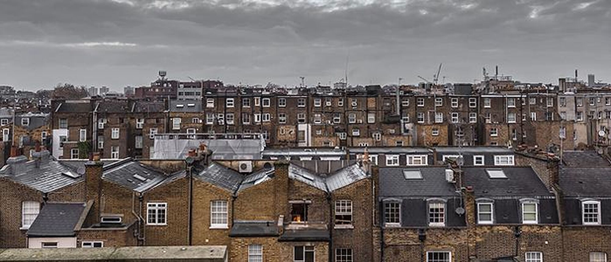 Rooftop view of old houses in London with grey sky and clouds. 700 pixels