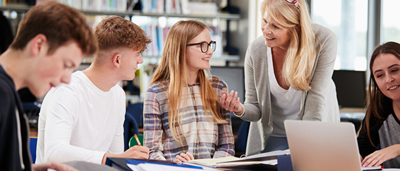 Image of students having a discussion with tutor in library