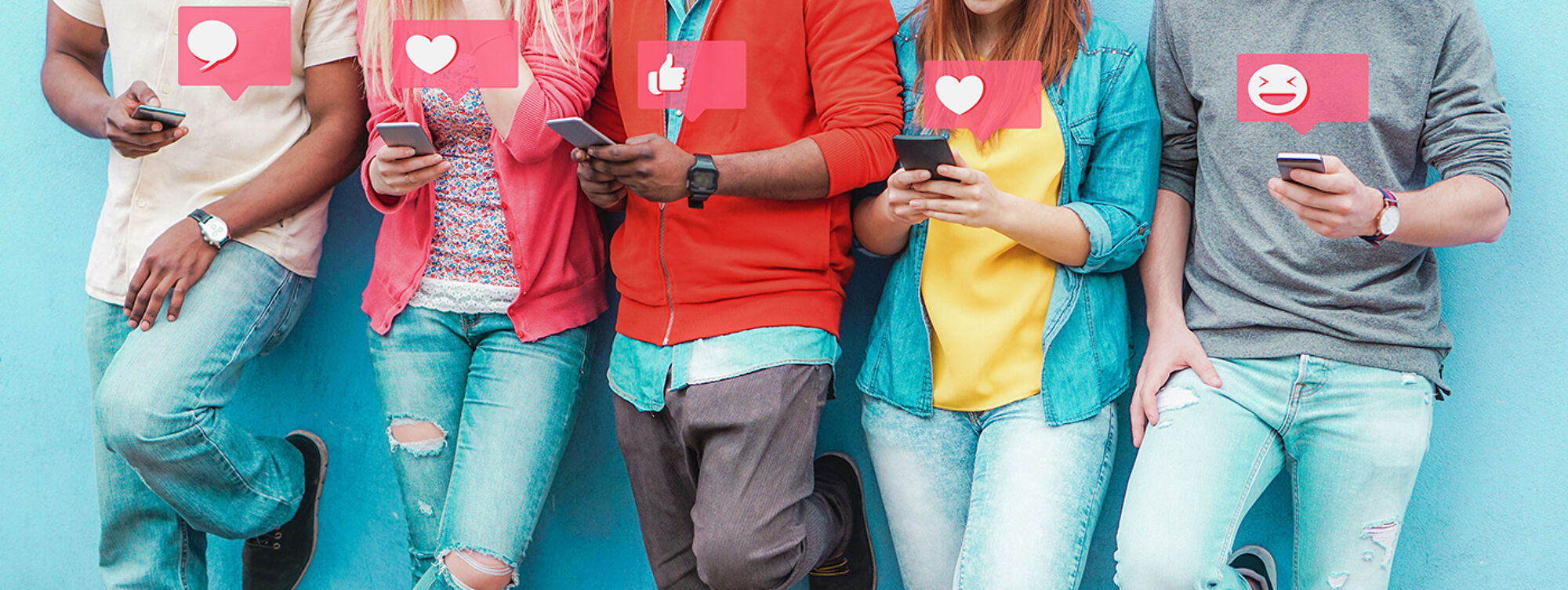 Young people standing in a row wearing bright clothes looking at social media on their mobile phones