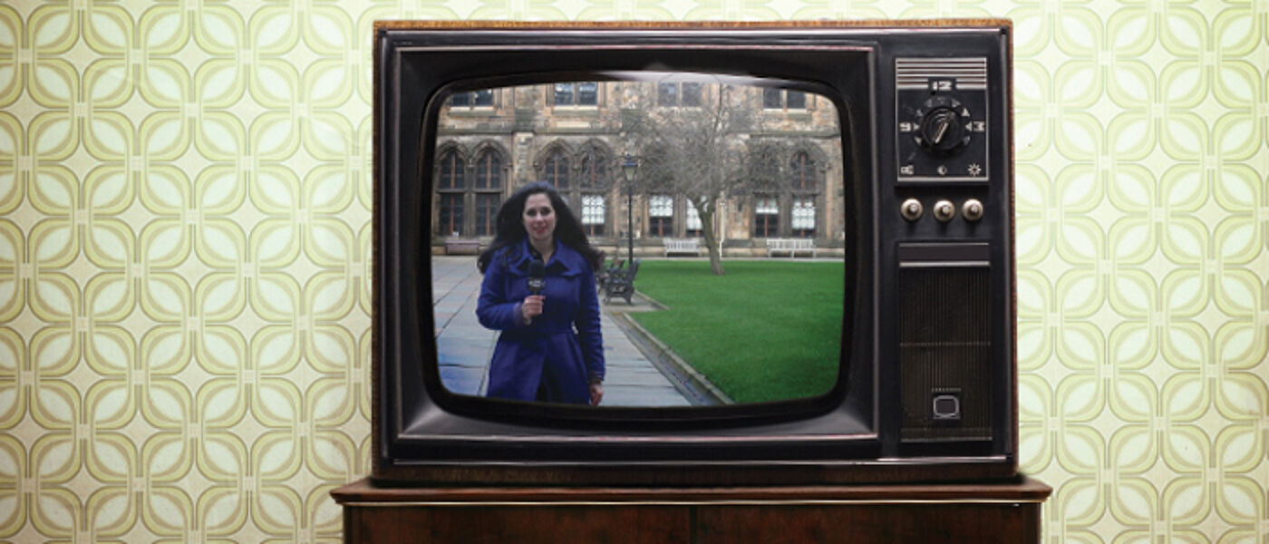 An old television and lounge scene with a modrn image from the Quadrangles upon it