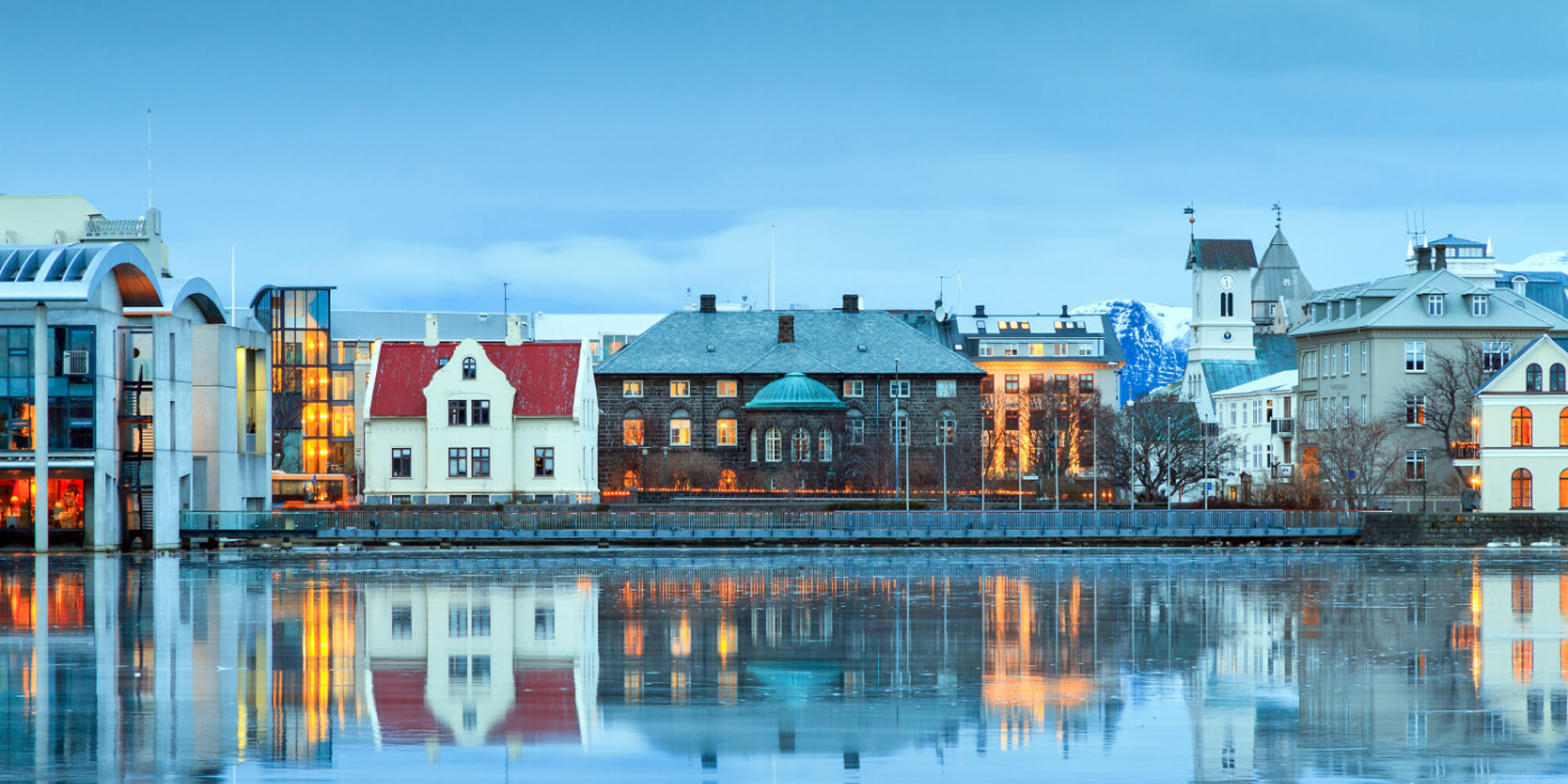 Reflection of the parliament house Althing of Reykjavik in lake Tjornin at the blue hour in winter.