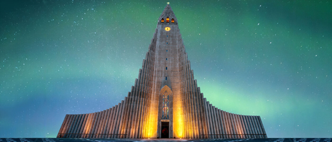 Exterior of the Hallgrímskirkja Church with a colourful aurora borealis in background.