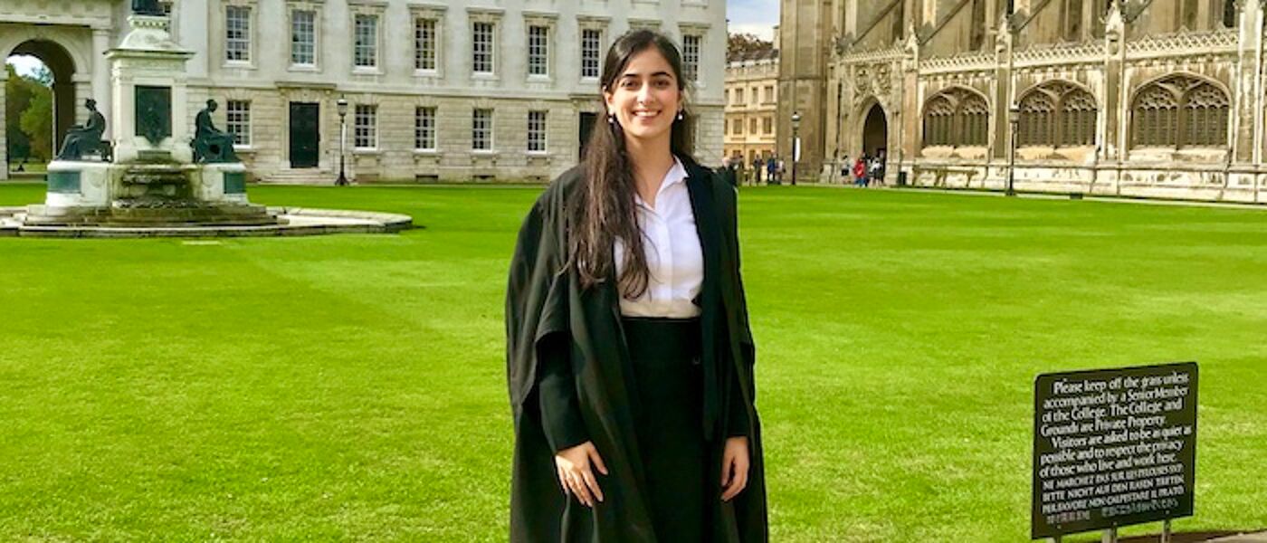 Young female graduate in front of Cambridge University lawns