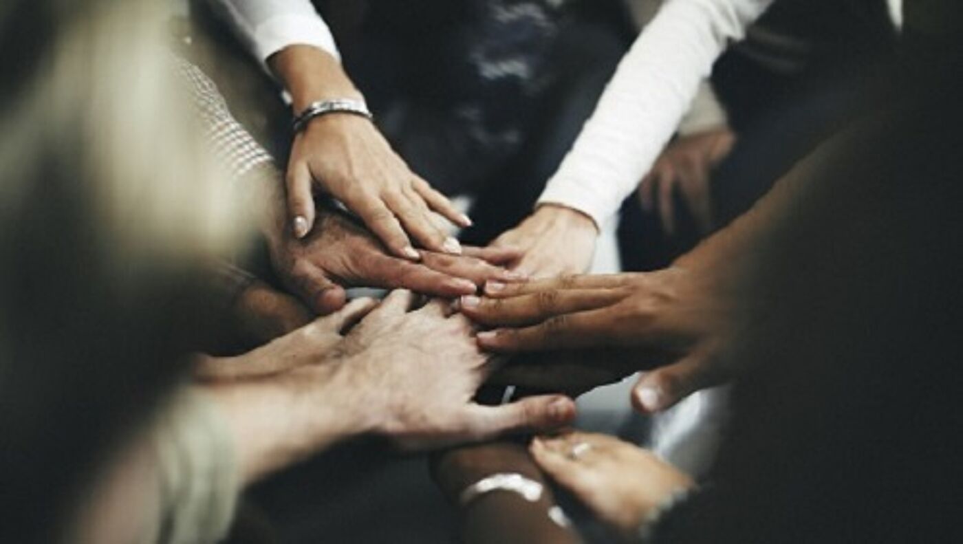 Different colour hands laid one on top of the other