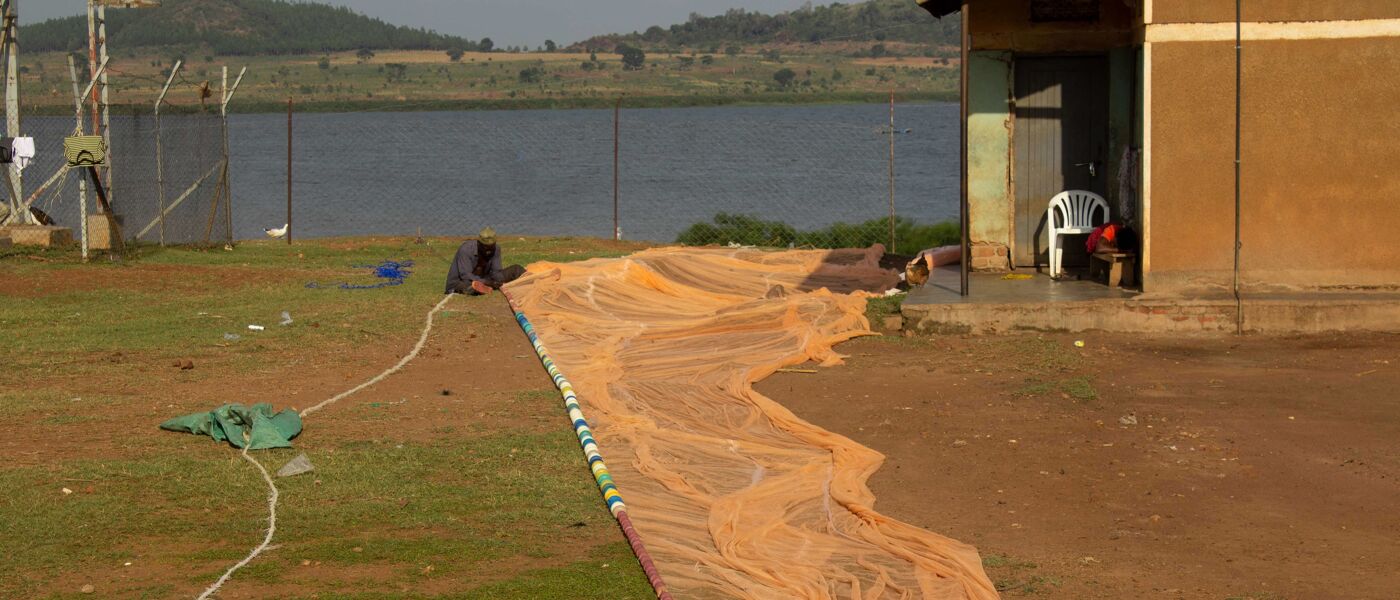 Man repairing a fishing net in rural Uganda