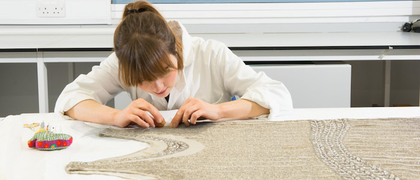 Student working on a dress in the conservation lab