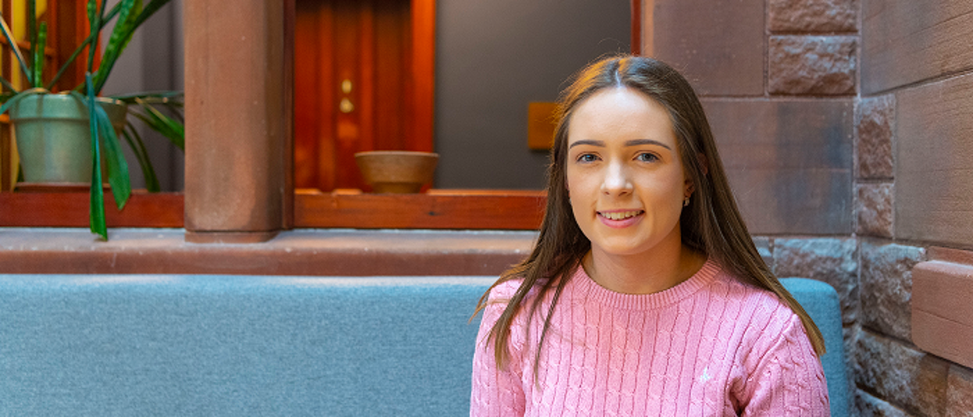 Hannah - student sitting in grey seats at study area