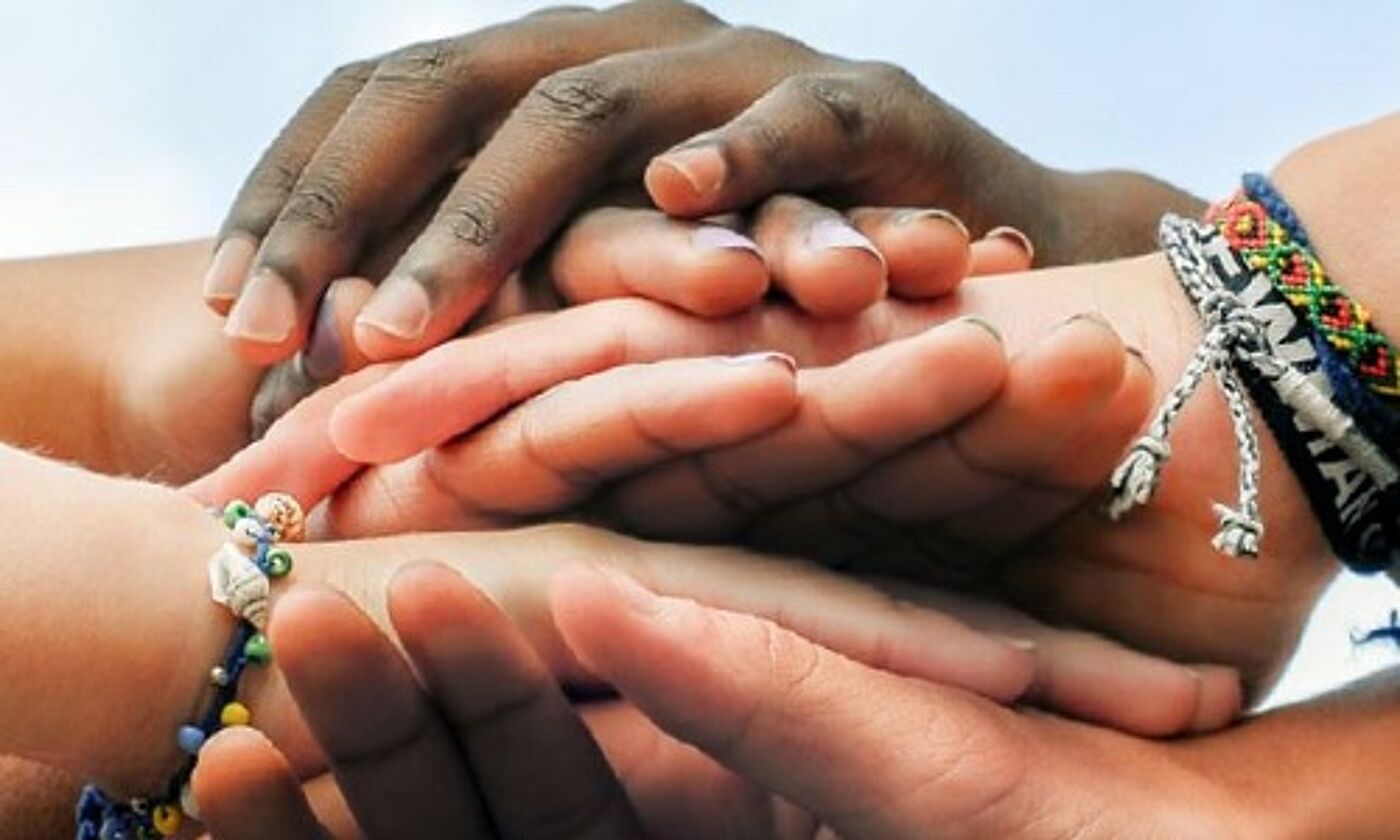 Many young hands of different colours one on top of the other