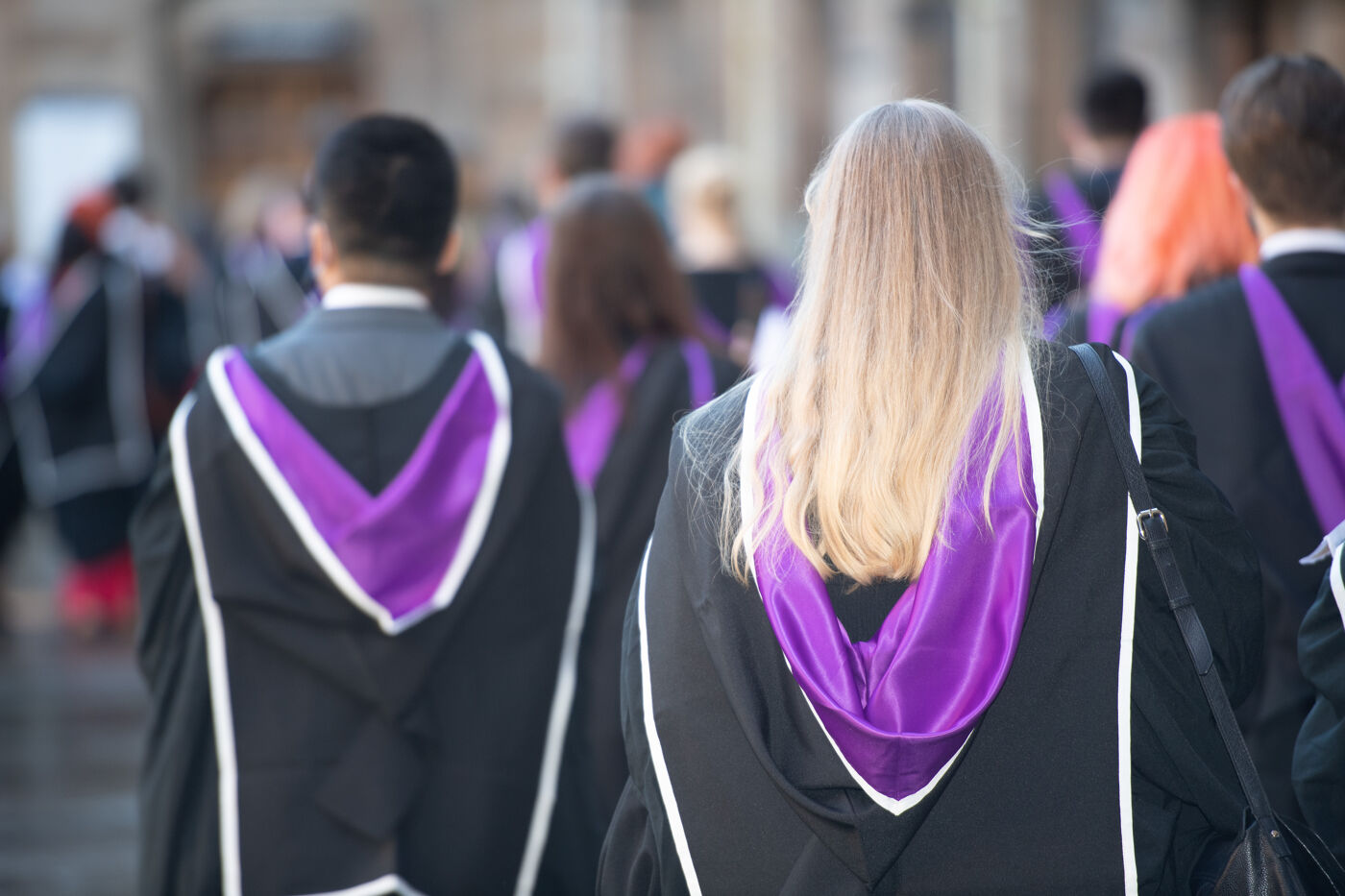 A rear view of two students walking to their graduation