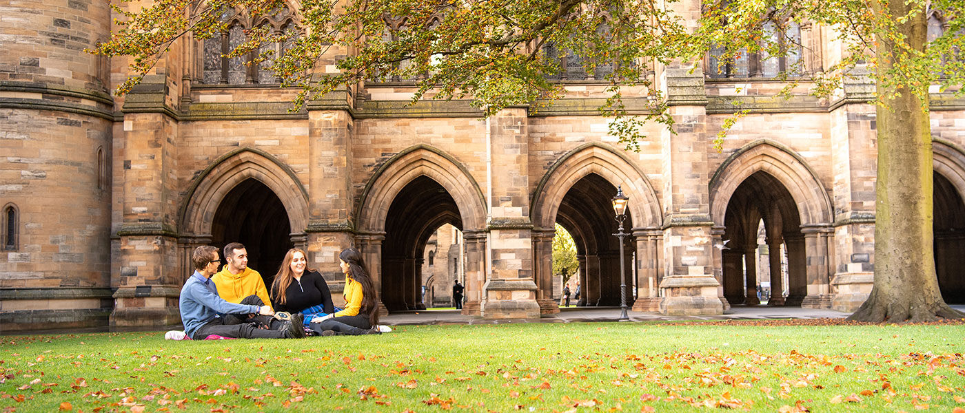 Students sitting on the grass beside the Cloisters