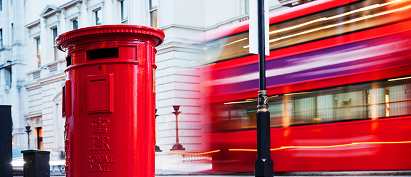 Traditional red mail letter box and red bus in motion in London, the UK. Symbols of the city and England