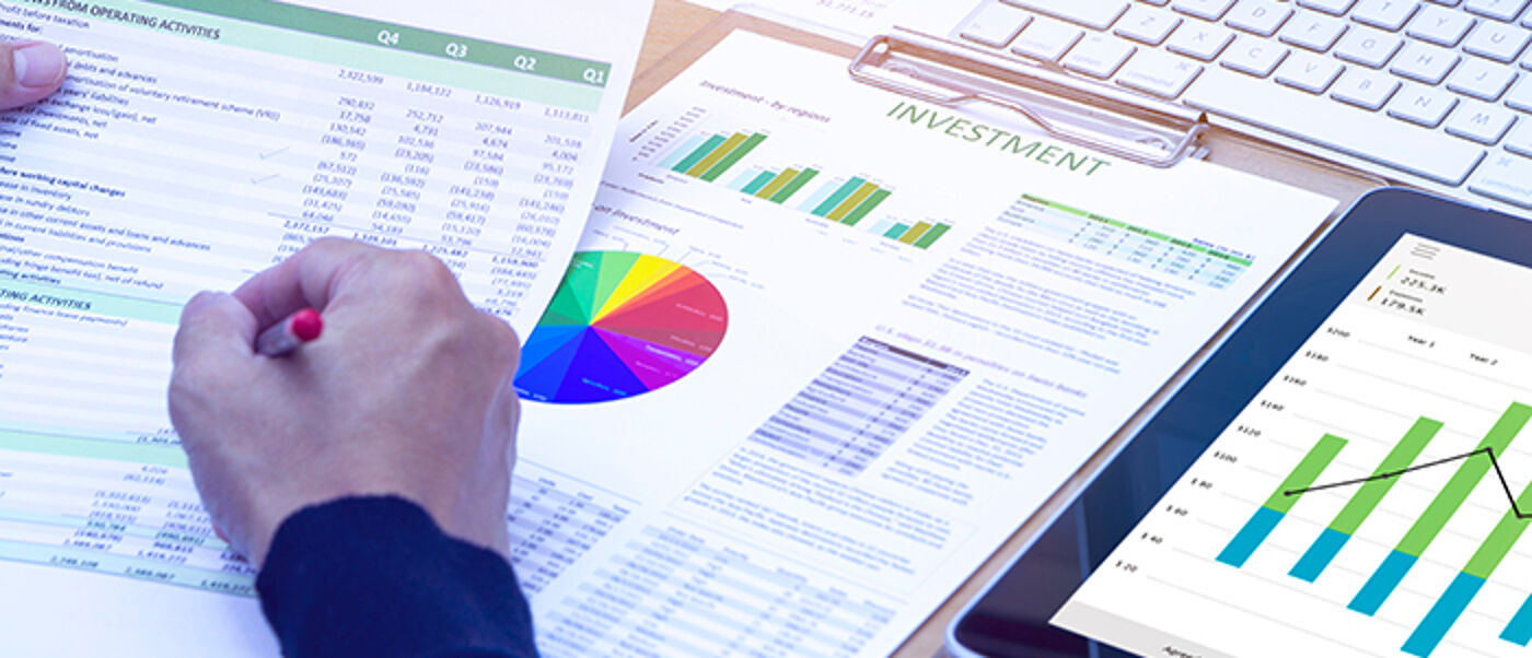 Businessman reviewing cash flow statement from investing activities in front of modern desktop computer.