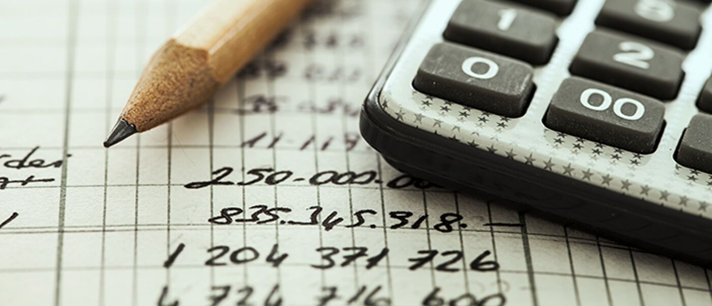 Calculator, notepad with numbers and pencil on a desk