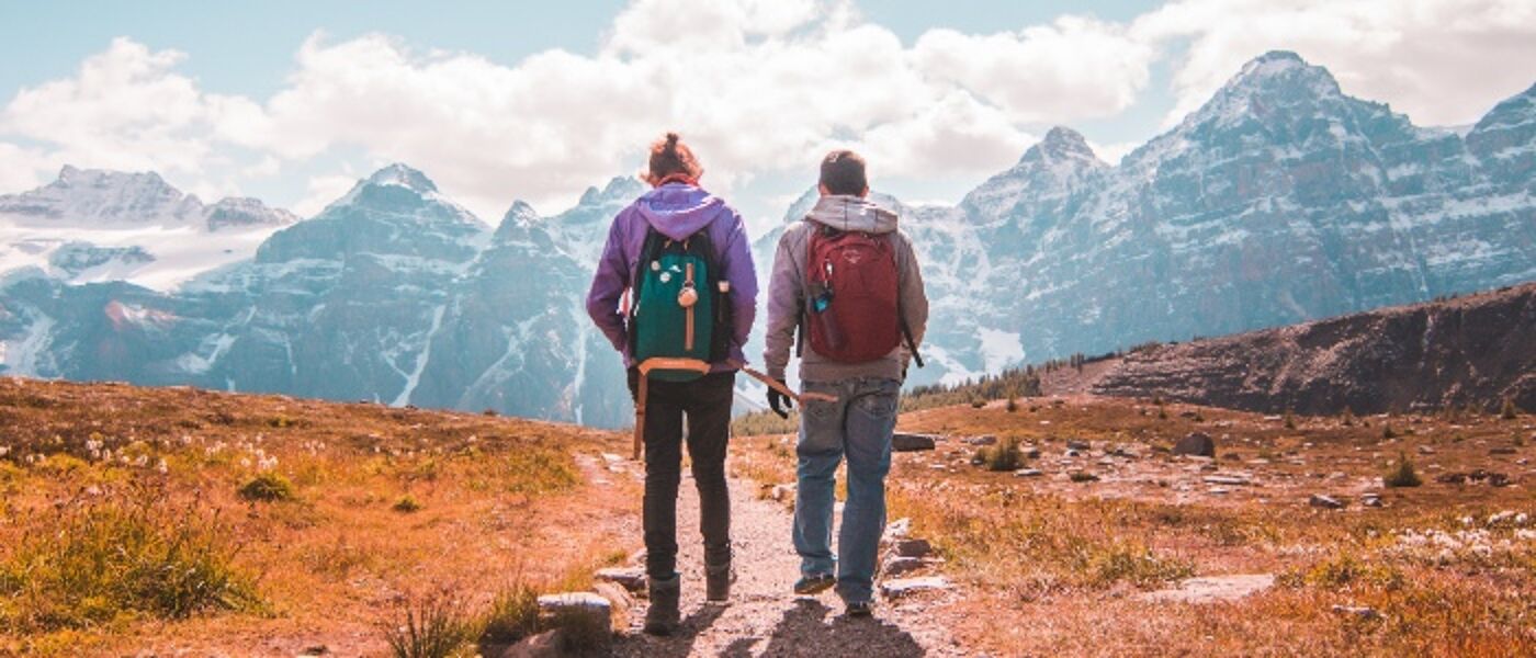 Two people walking in Canada with snowy mountains ahead