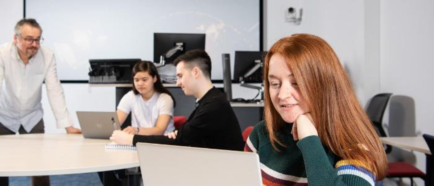 Three Graduate Apprentices using laptops and learning from tutor