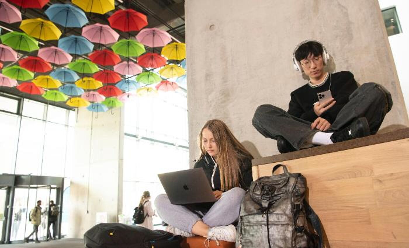 Students sitting cross legged on steps indoors