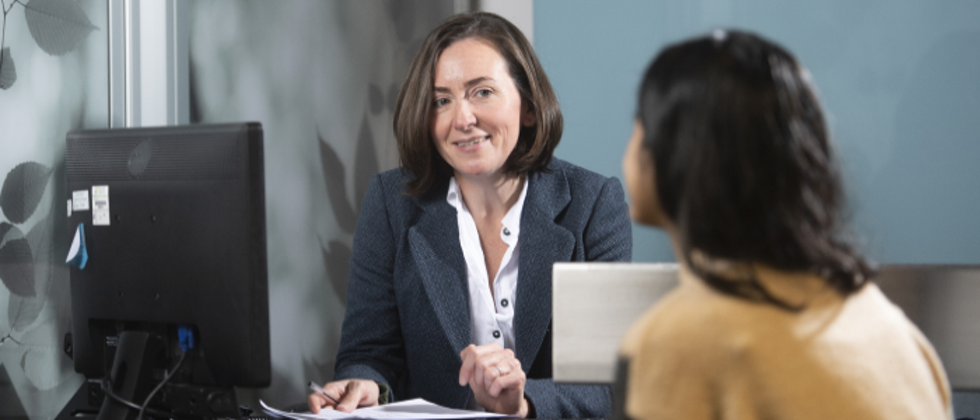 Two females sitted in discussion across a service desk