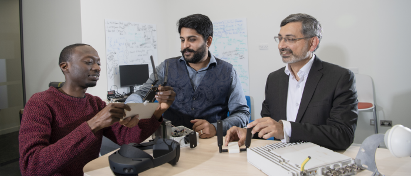 three men sitting around equipment talking about research