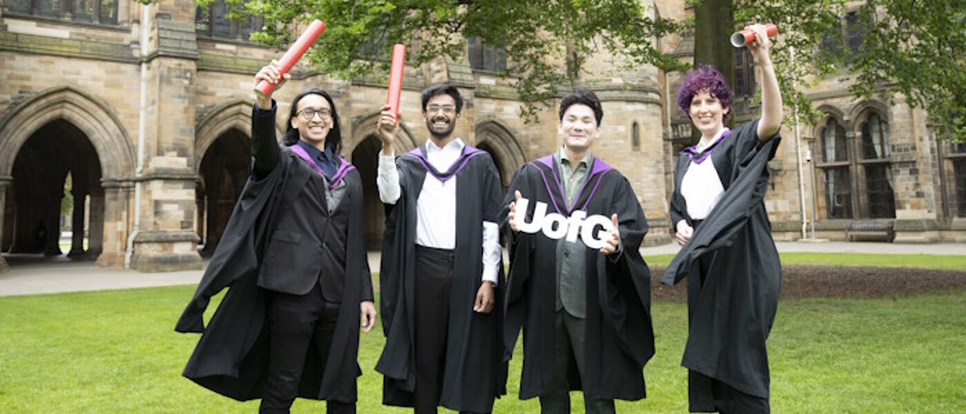 Students celebrating holding scrolls in the quadrangle during graduation