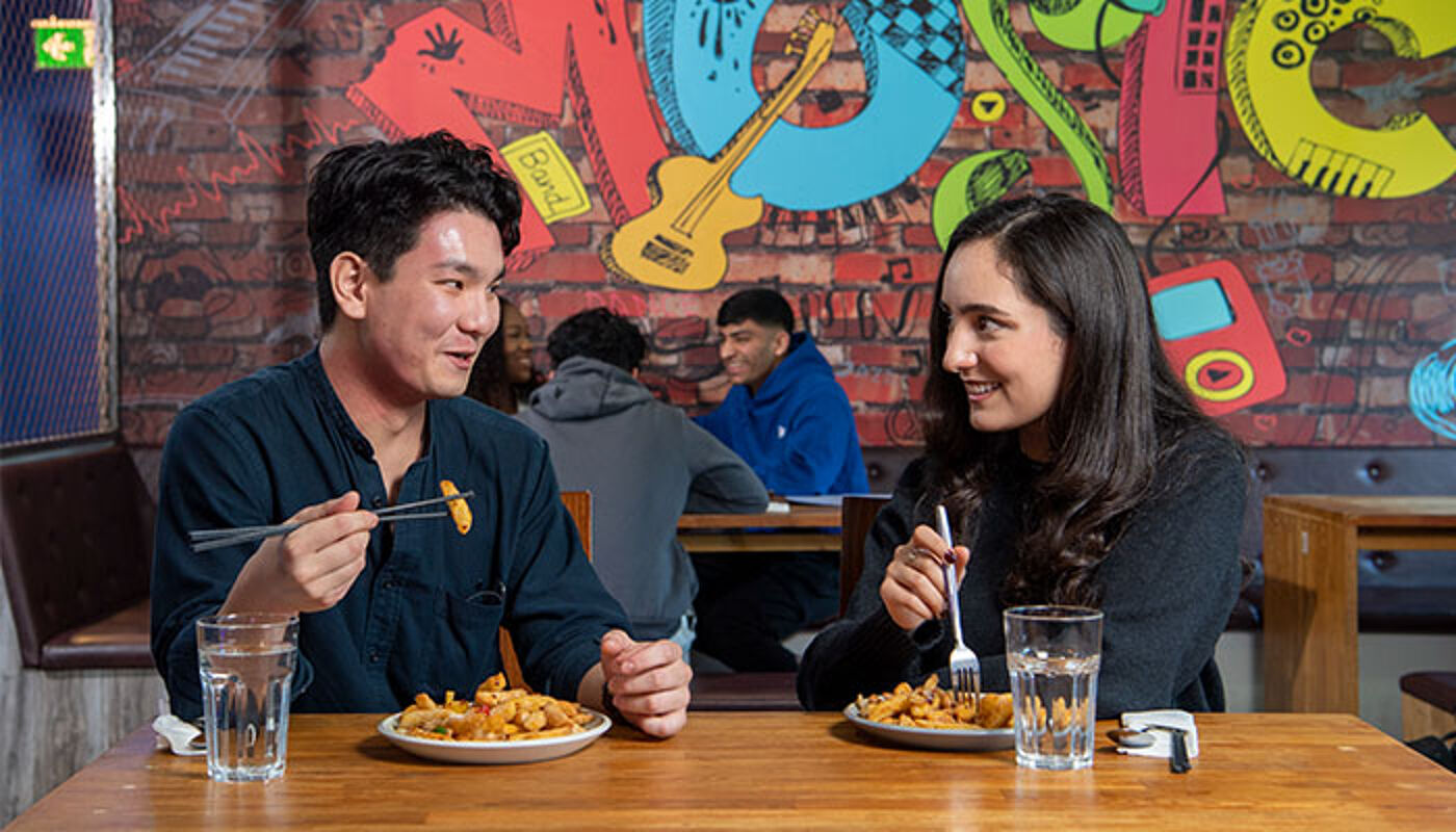 Two students eating a meal in QMU