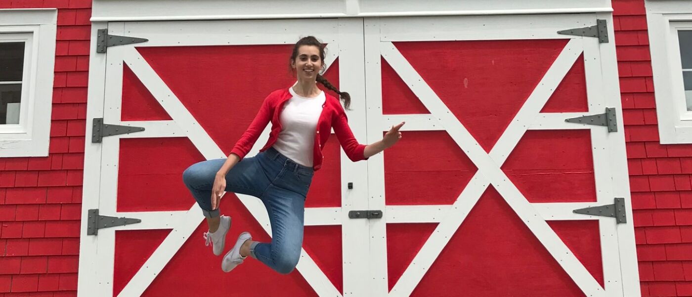 Anna Sollazzo jumping in front of a big red door
